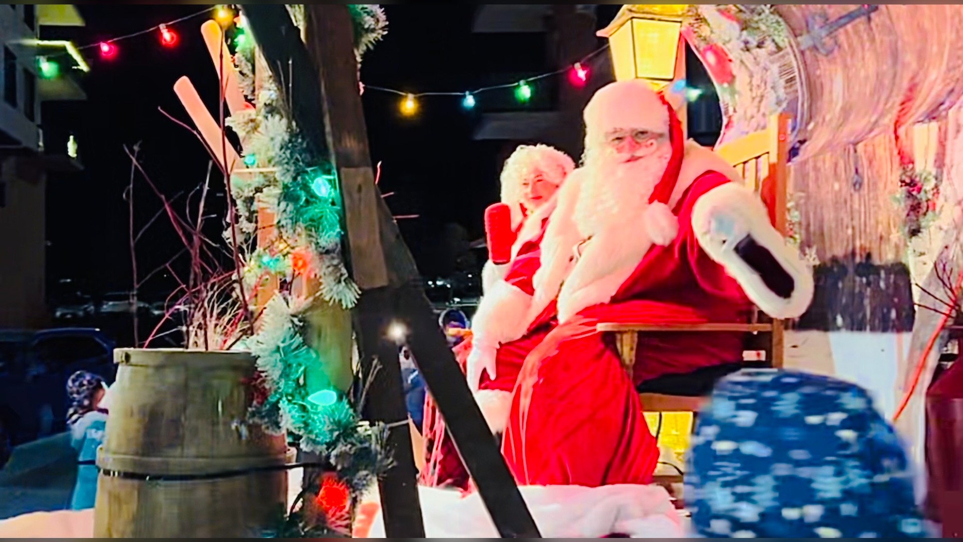 Santa Claus sits next to Mrs. Claus on a parade float.