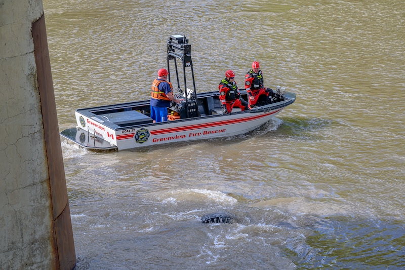 An emergency crew searches the water under the Wapiti River Bridge after a commercial crane drove off the bridge and went into the water, near Grande Prairie, Alta., on Tuesday, June 16, 2026. THE CANADIAN PRESS/William Vavrek
